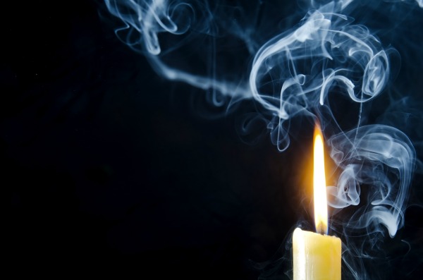 Burning candle and smoke on a dark background.