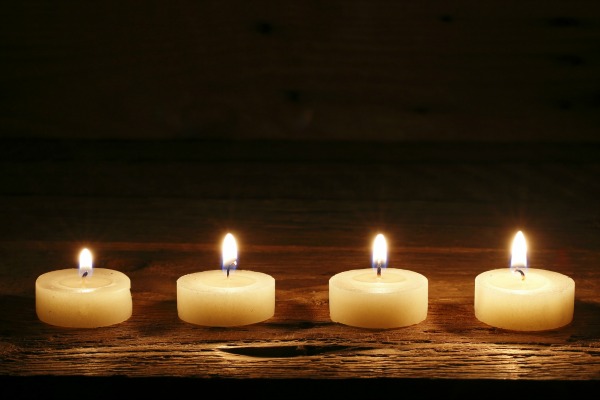 four burning candles on wood