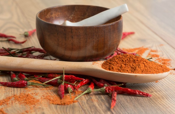 red hot pepper chili powder in a mortar and pods on a wooden table